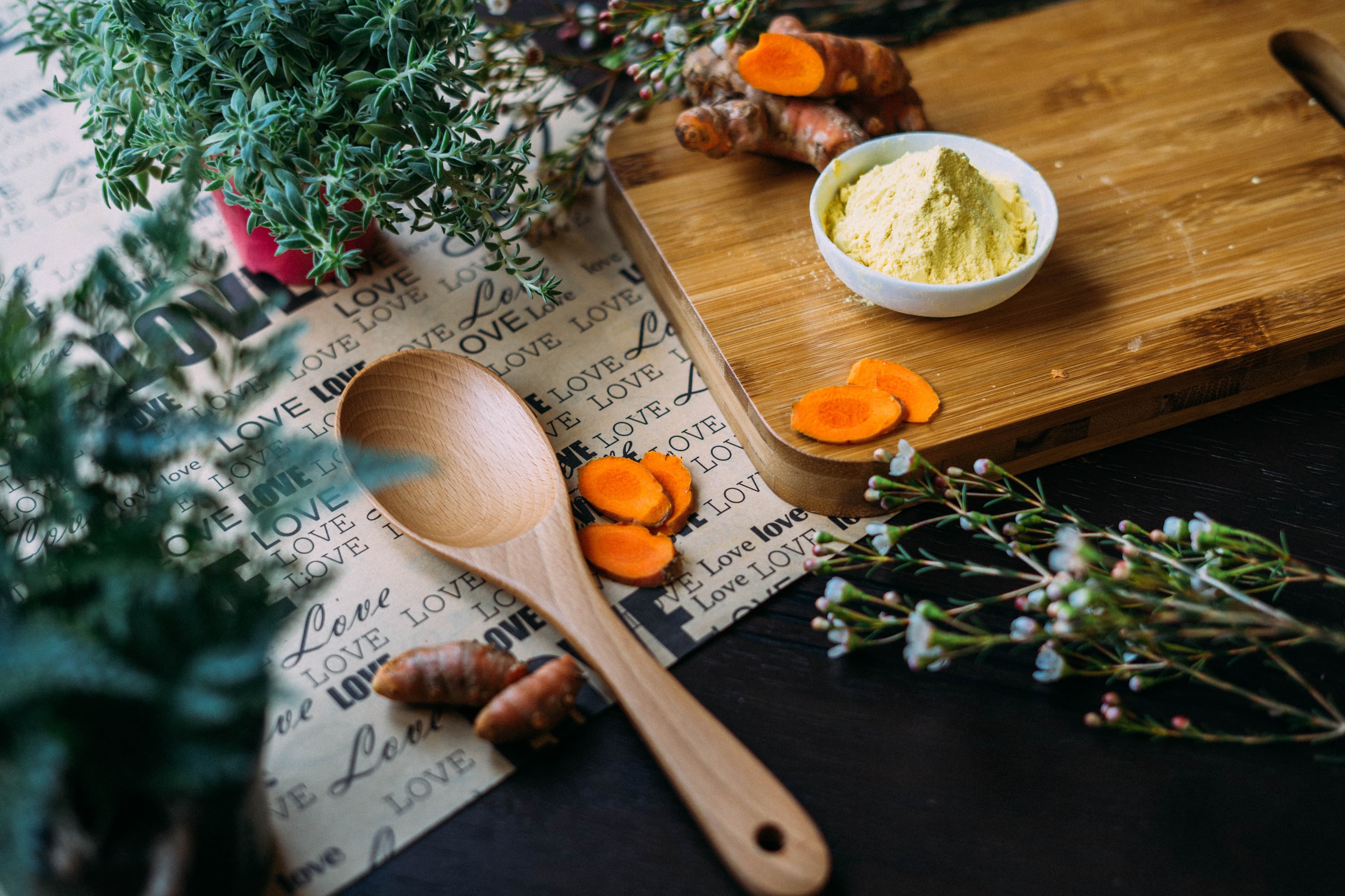 Small bowl filled with orange, powered herb, surrounded by plants
