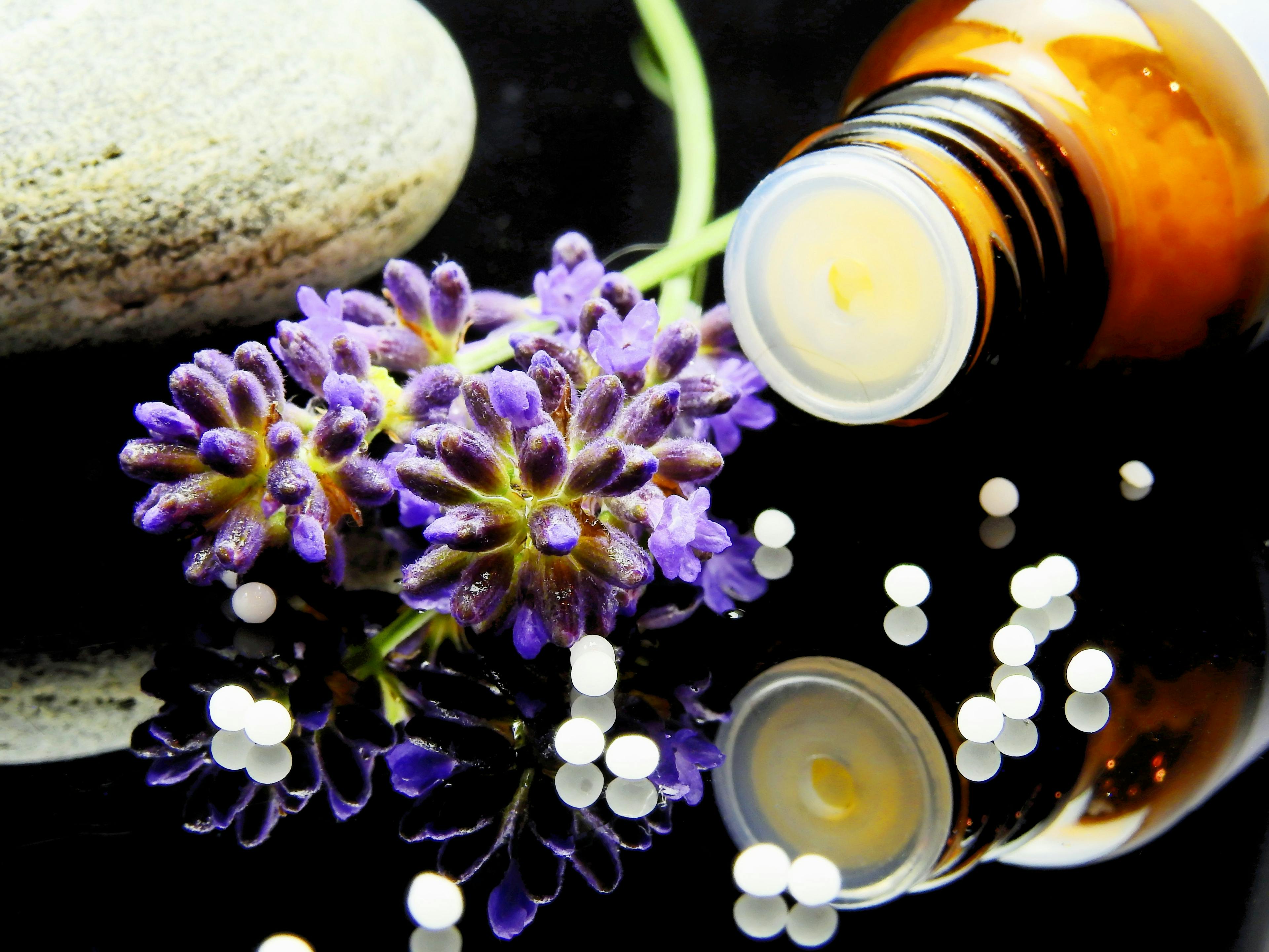 Bottle of homeopathy spilling out onto table with flowers