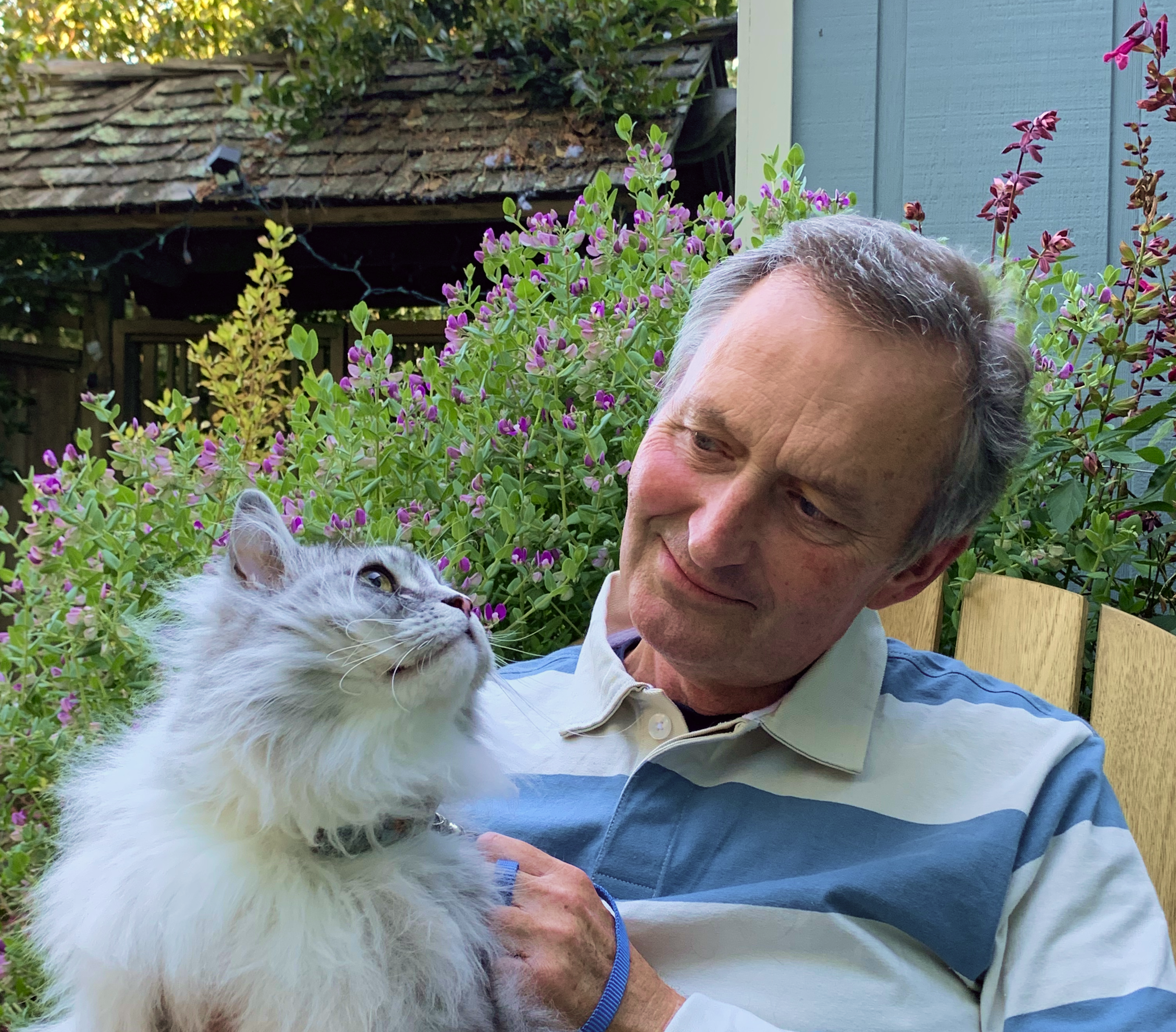 Dr. Noel Crymble sitting down, smiling, holding fluffy gray cat